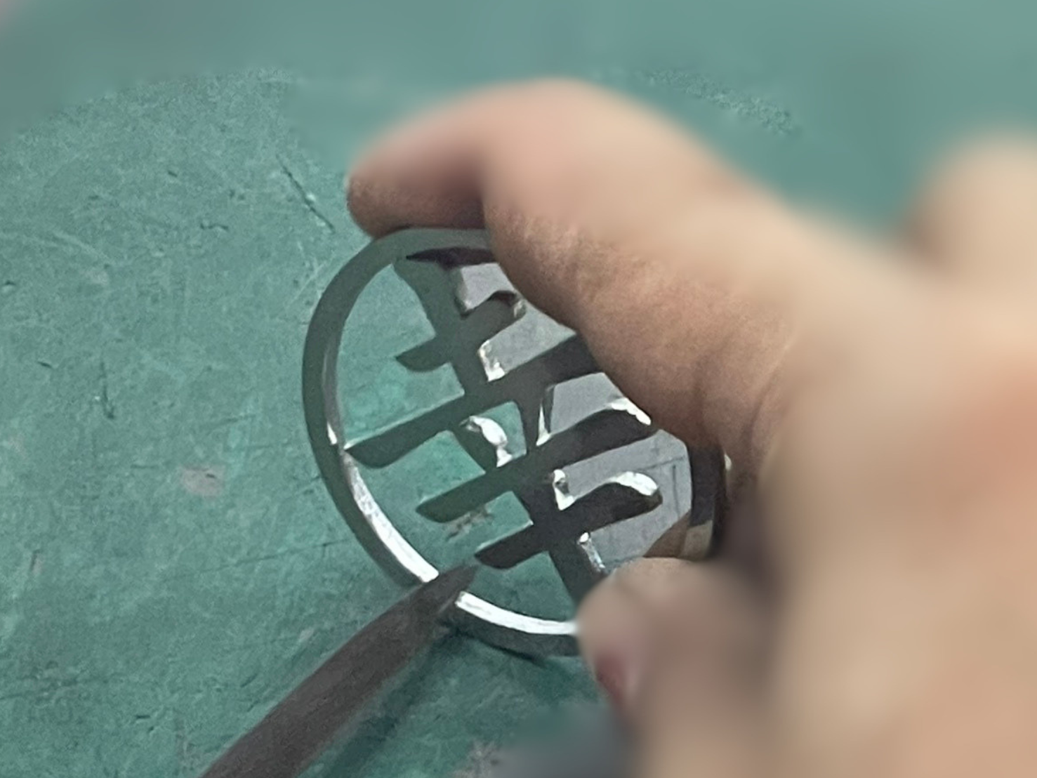 ステンレスのゴルフマーカーをやすりをかけている手元